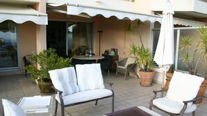 Un patio con due poltrone bianche imbottite, un tavolino e piante in vaso.