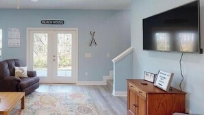 Ein Wohnzimmer mit einer Couch, einem Teppich, einem Fernseher und einem Schild, das die Verfügbarkeit von WLAN anzeigt.