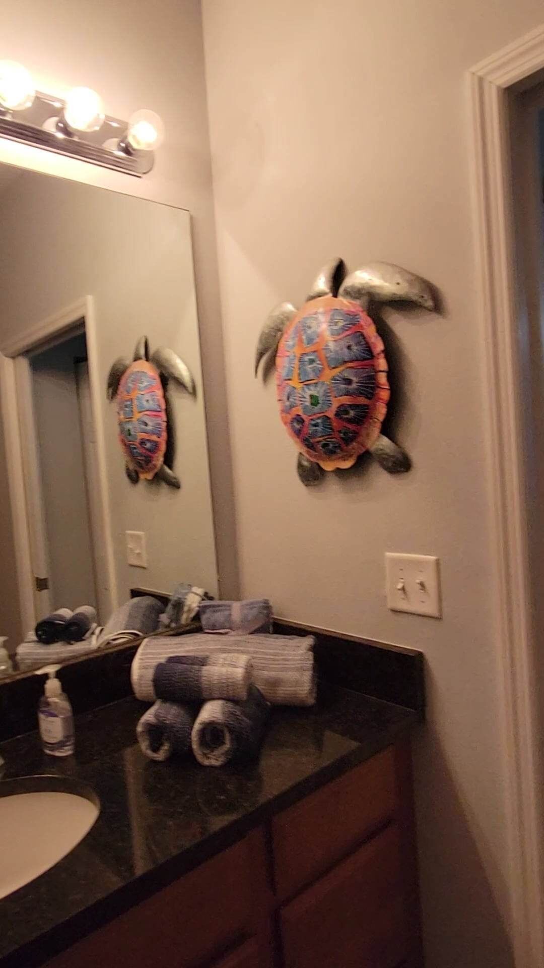 Un baño con un espejo grande, un perchero para toallas y un lavamanos.