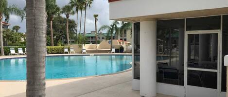 Zona de piscina con sillones de descanso y palmeras.