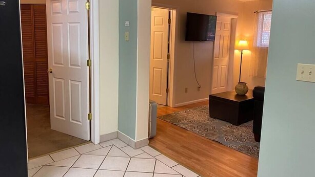 A hallway with a tiled floor, a wooden door, a white door, and a television mounted on the wall. - #2 (Water) Home in the Heart of Utah- You are part of our community (Torrey)