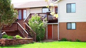 A two-story residential building with a front deck, a stone retaining wall, and a well-maintained lawn. - #2 (Water) Home in the Heart of Utah- You are part of our community (Torrey)