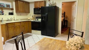A compact kitchen with wooden cabinets, a black refrigerator, and a dining table with chairs. - #2 (Water) Home in the Heart of Utah- You are part of our community (Torrey)