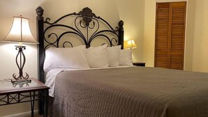 A neatly made bed with a dark metal headboard, two bedside lamps, and a wooden door in a hotel room. - #2 (Water) Home in the Heart of Utah- You are part of our community (Torrey)