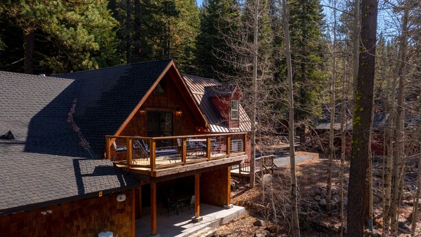 Eine Holzhütte mit Balkon, umgeben von Bäumen.