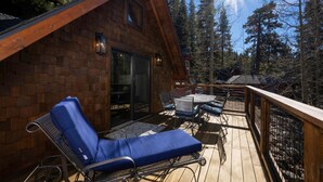 Eine Holzhütte mit einer Terrasse, einem Liegestuhl und einem Tisch mit Stühlen.