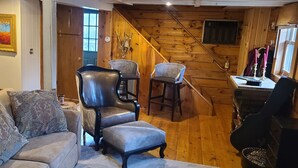A cozy living room with a sofa, two armchairs, a wooden staircase, and a guitar. - COZY CABIN AT PATOKA LAKE(in happy hollow) (Birdseye)