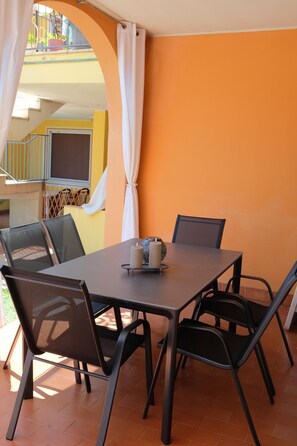 Un patio al aire libre con una mesa, sillas, una vela y vistas a un edificio amarillo con balcón.