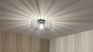 Een woonkamer met een flatscreen televisie, een witte tv-meubel, een decoratieve vaas en drie ingekaderde kunstwerken aan de muur.