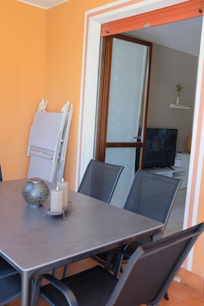 A dining area with a table, chairs, and a television in the background. - La Meridiana App. 04 - The Perfect Spot for a Relaxing Vacation (Peschiera del Garda)