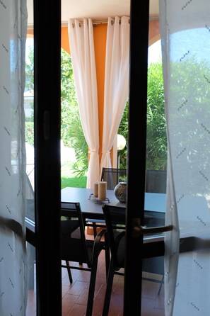 Un comedor interior con una mesa, sillas y vistas a zonas verdes.