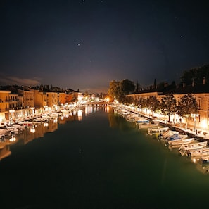 A nighttime view of a canal lined with boats and buildings. - La Meridiana App. 04 - The Perfect Spot for a Relaxing Vacation (Peschiera del Garda)