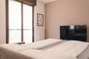 Une chambre d’hôtel avec un lit, une télévision et une fenêtre équipée de stores.