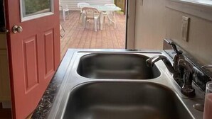 A kitchen with two stainless steel sinks, a window, and a door leading to an outdoor patio with a table and chairs. - #6 Home in the Heart of Utah (Torrey)