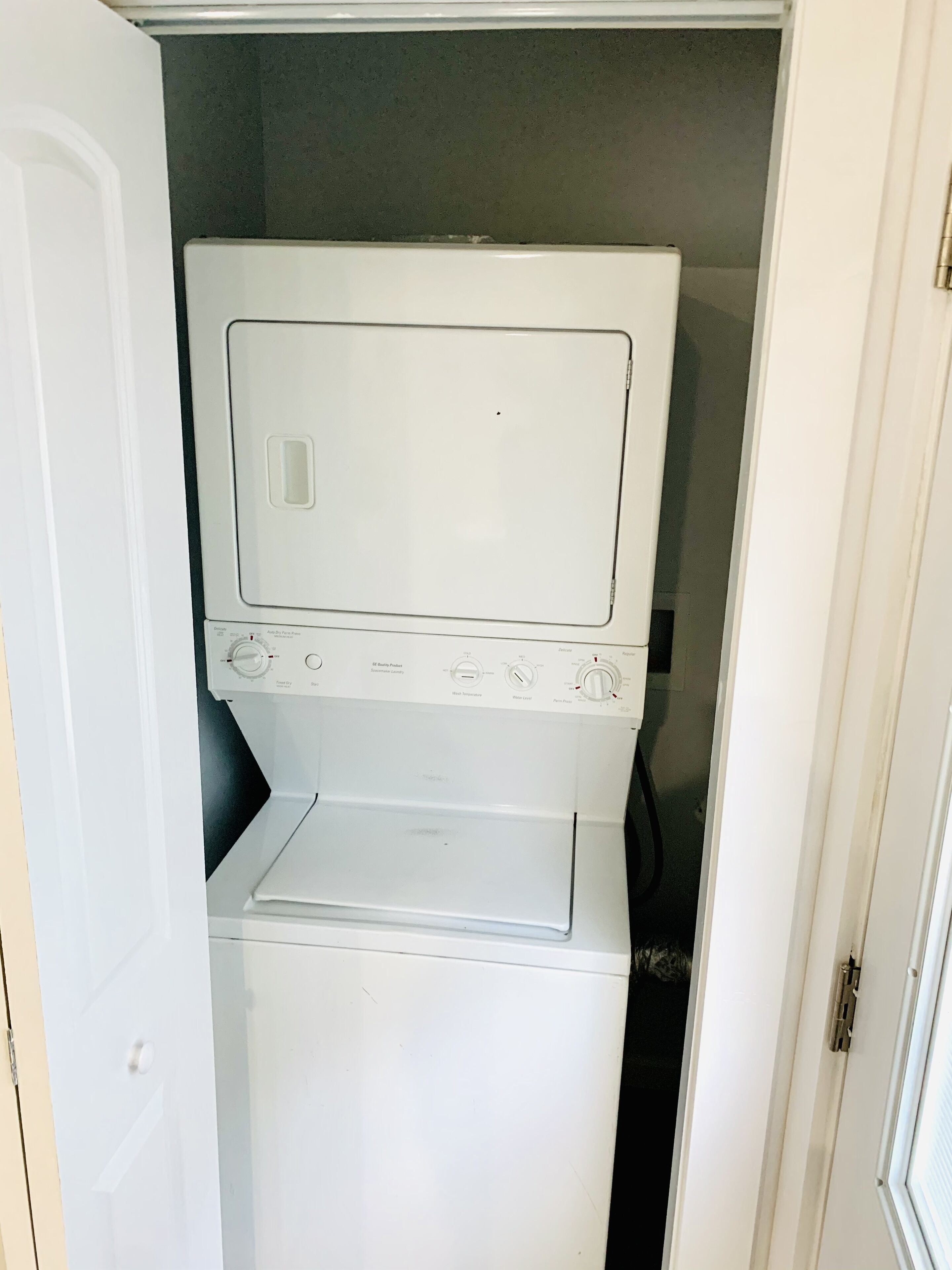 A compact laundry room with a top-loading washing machine and a front-loading dryer.