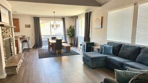 A modern living room with a sectional sofa, dining area, and a fireplace. - Checkout our weekday discount! w/Central AC. (Big Bear)