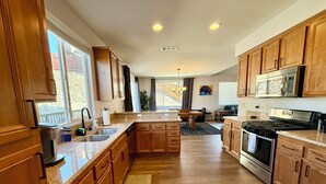A modern kitchen with wooden cabinets, a stainless steel stove, and a large island. - Checkout our weekday discount! w/Central AC. (Big Bear)