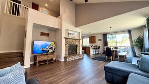 A spacious living area with a fireplace, a television, and a dining area with a view of the outdoors. - Checkout our weekday discount! w/Central AC. (Big Bear)