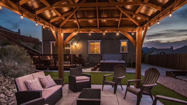 An outdoor patio with wicker furniture, a covered seating area, and a view of a house in the background. - Checkout our weekday discount! w/Central AC. (Big Bear)