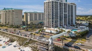 A high-rise hotel with multiple floors, a pool, and a beach area with umbrellas. - Coastal Bliss and Million Dollar Views (Miramar Beach)