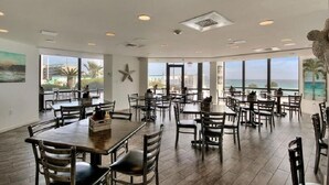 A spacious dining area with multiple tables and chairs, large windows offering ocean views, and a star decoration on the wall. - Coastal Bliss and Million Dollar Views (Miramar Beach)