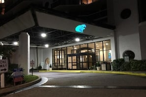 Hotel entrance with illuminated logo and modern architectural design.