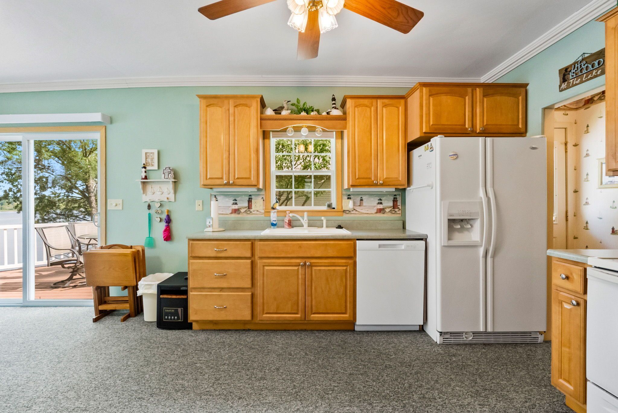 A kitchen with wooden cabinets, a white refrigerator, and a window with a view of trees.