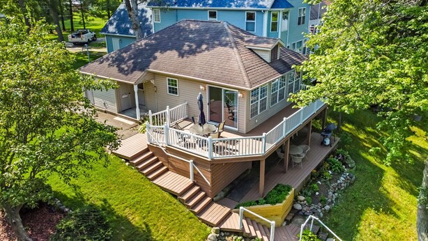 A two-story house with a deck, a covered patio, and a small garden area. - Lakefront Cottage on Webster Lake with Beautiful Sunsets, 2 bed, 1 bath (North Webster)
