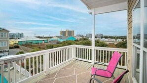 A balcony with a white railing, a pink chair, and a view of buildings in the distance. - Blue Water; Oceanview condo, Atlantic Beach (Atlantic Beach)