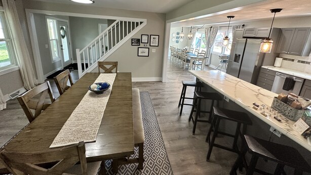 A spacious kitchen with a long dining table, a staircase leading to another level, and a view of the backyard.