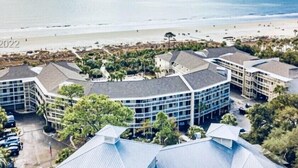 Ein Küstenhotel mit geschwungener Architektur, einem Parkplatz und Blick auf den Strand.
