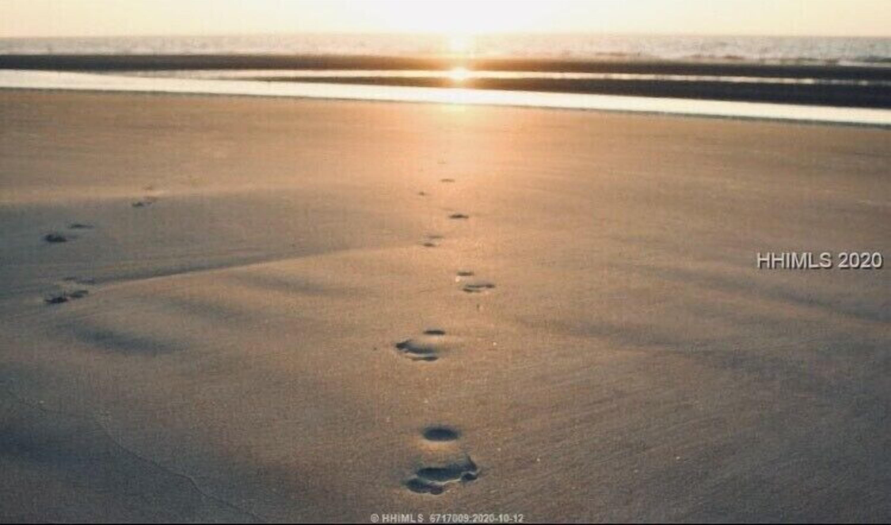 A beach with footprints leading towards the ocean at sunset.