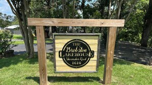 A wooden sign with the text "The Broxton Lakehouse Shoenacher Road 1610" indicating a property name and address. - Lakehouse with Dock (Benton)