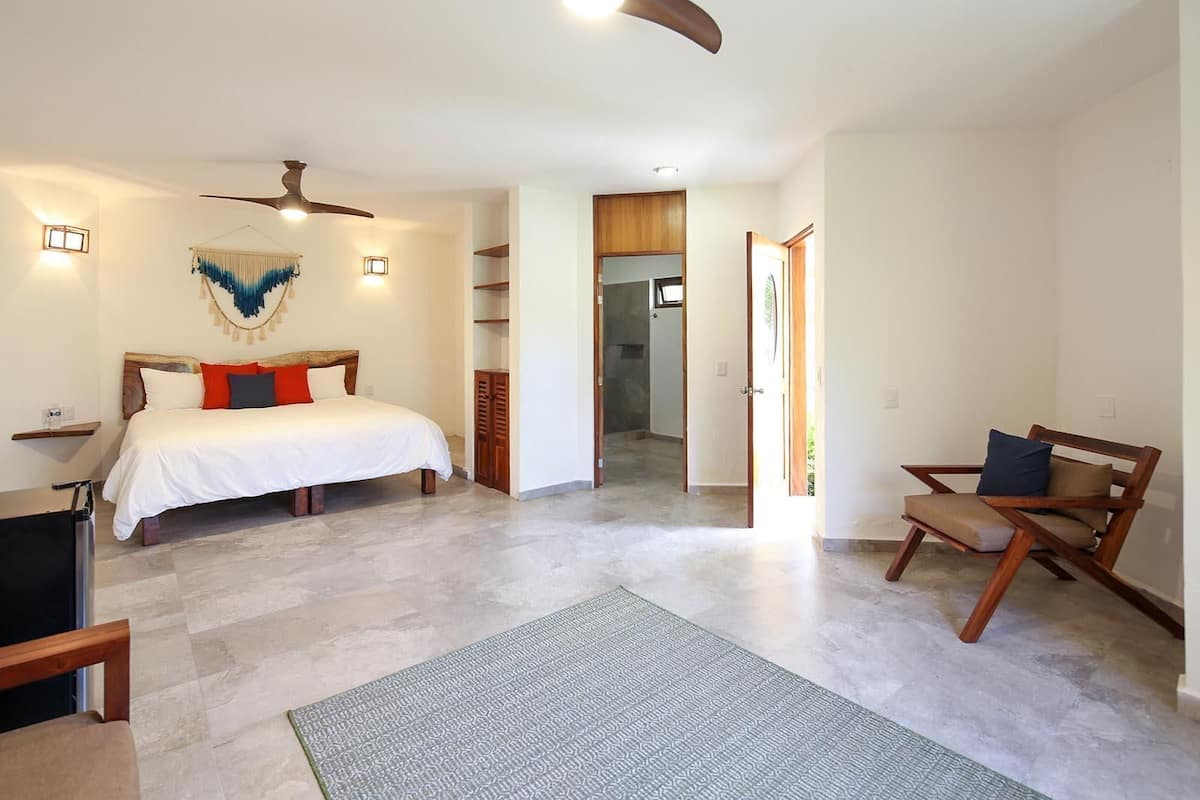 A bedroom with a bed, a chair, a desk, and a ceiling fan.