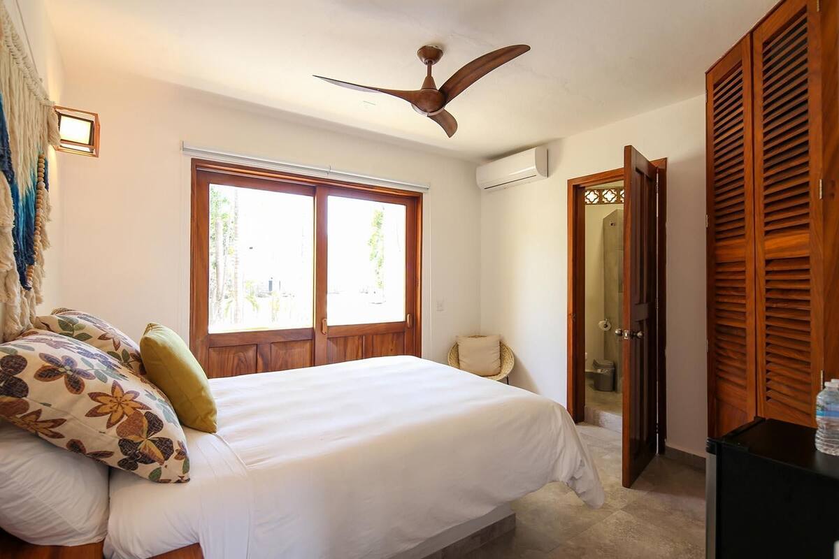 A bedroom with a bed, a ceiling fan, a window, and a wardrobe.