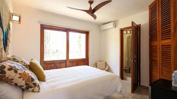 A bedroom with a bed, a ceiling fan, a window, and a wardrobe.