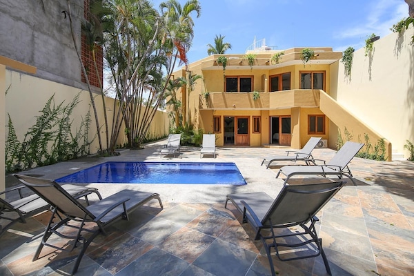 Una piscina al aire libre, sombrillas, sillones reclinables de piscina
