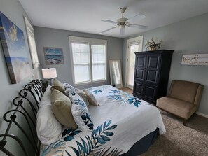 A bedroom with a bed, a chair, a wardrobe, and a ceiling fan.