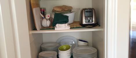 A kitchen pantry with shelves containing a blender, toaster, coffee maker, and various kitchen utensils.