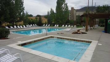 A pool area with two rectangular pools, lounge chairs, and a pergola.