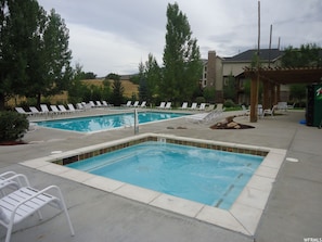 A pool area with two rectangular pools, lounge chairs, and a pergola. - Powder Mountain Family Friendly Condo @ Moose Hollow Sleeps 6! (Eden)