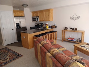 A compact living space with a kitchenette, a sofa, a coffee table, and a rug. - Powder Mountain Family Friendly Condo @ Moose Hollow Sleeps 6! (Eden)