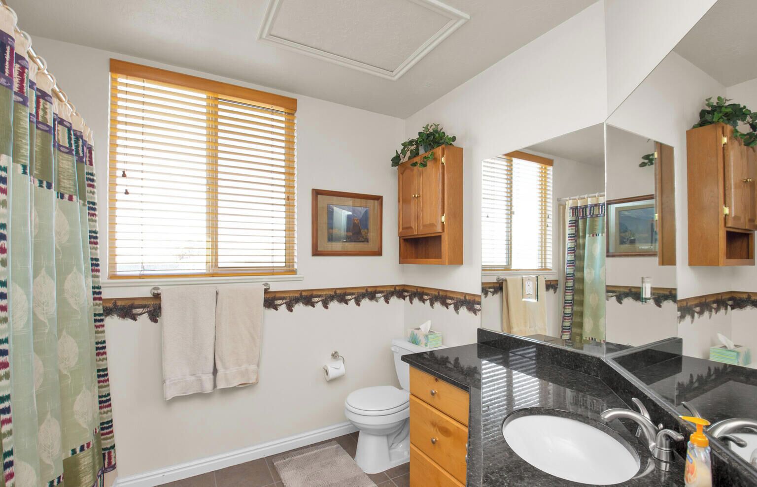 A bathroom with a toilet, sink, and wooden cabinets.