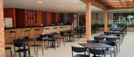 A spacious indoor area with multiple tables and chairs arranged for dining.