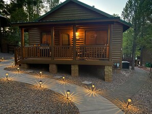 A log cabin with a porch, surrounded by gravel and trees. - Rim Country Cabin, sleeps 4. (Show Low)
