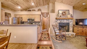 Una cocina amplia con armarios de madera, una chimenea de piedra y un televisor grande.