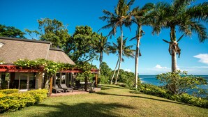 A house with a covered patio, a lawn, and palm trees. - Malaqereqere Ocean View, Villa 2 (Sigatoka)
