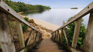 A wooden staircase leading to a beach with a calm sea and a small island in the distance. - Malaqereqere Ocean View, Villa 2 (Sigatoka)