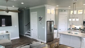 A modern kitchen with white cabinetry, a stainless steel refrigerator, and a marble countertop. - Gorgeous Beach View - 2nd Street back  - 4/3 2 Story (Galveston)