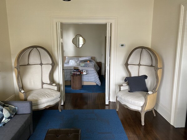 A hotel room with a bed, two armchairs, a small table, and a blue carpet.